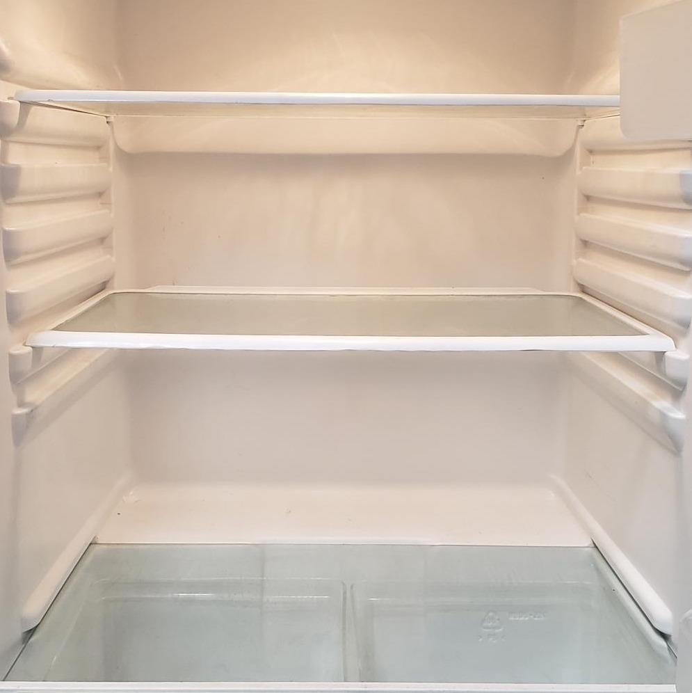 The white artificially lit interior of a clean, empty fridge.