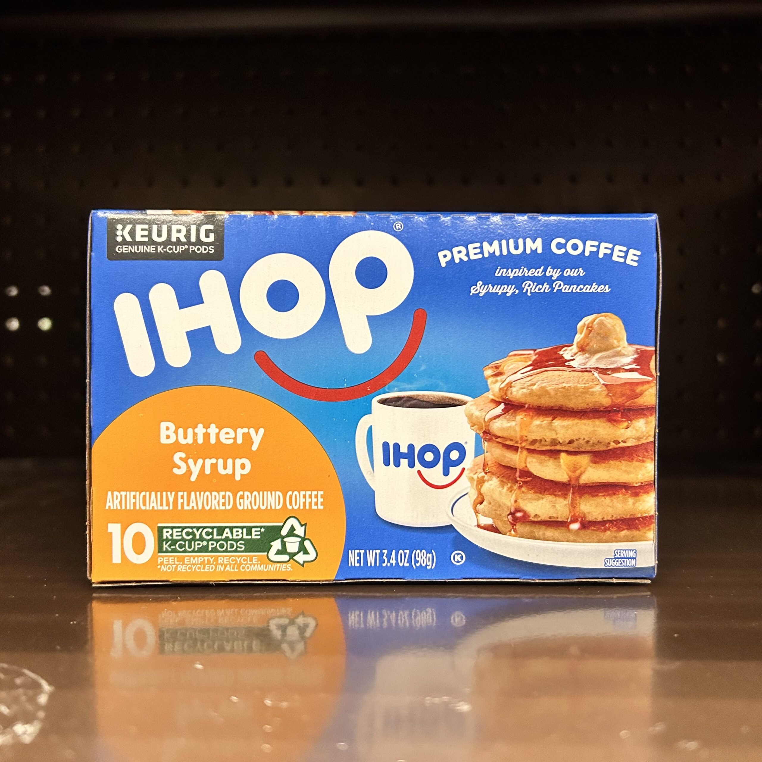 A blue box of IHOP buttery syrup flavored coffee, showing the IHOP logo, an IHOP cup, and a stack of pancakes.